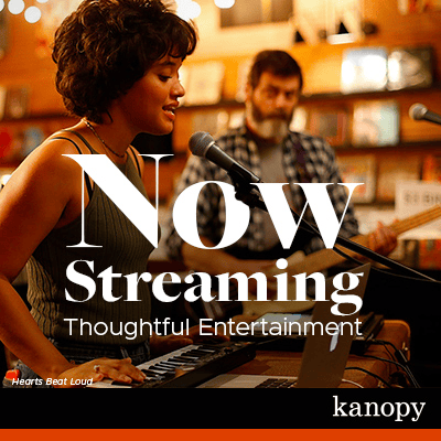 A woman plays a keyboard and sings into a microphone, with a man playing guitar in the background. Text reads: Now Streaming Thoughtful Entertainment. Hearts Beat Loud. Kanopy.
